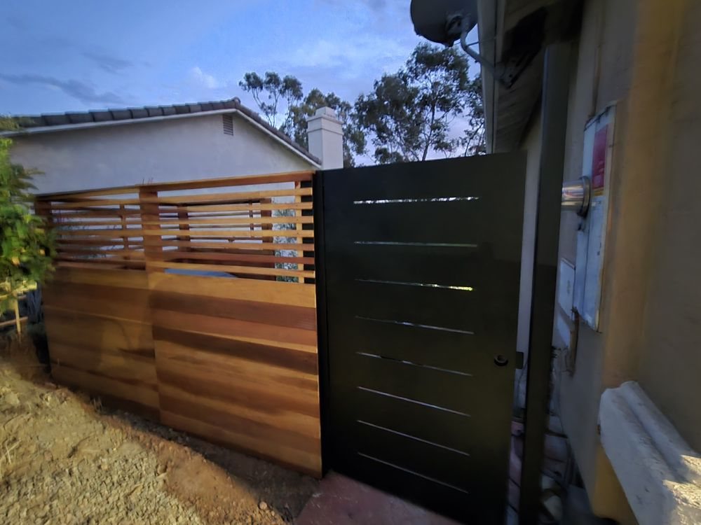 Modern horizontal wood fence with a black metal driveway gate built by Mitre's Fence in San Marcos