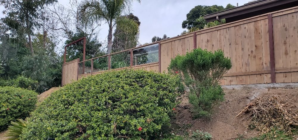 Wood fence with inset glass panels on a hillside lot
